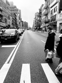 a black and white photo of people crossing a street