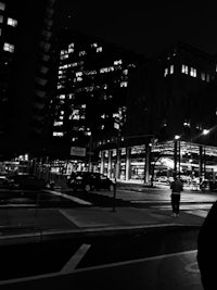 a black and white photo of a man crossing a street at night