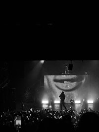 a black and white photo of a man on stage at a concert